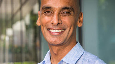Salil Vadhan. Headshot. Salil is in a sunny indoor location. He is bald, with medium-brown skin. He is facing the viewer and smiling broadly.